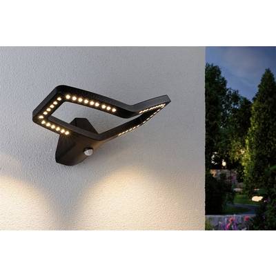 Modern black outdoor light on a white wall; illuminates the garden area in the evening with warm lights directed towards the ground.