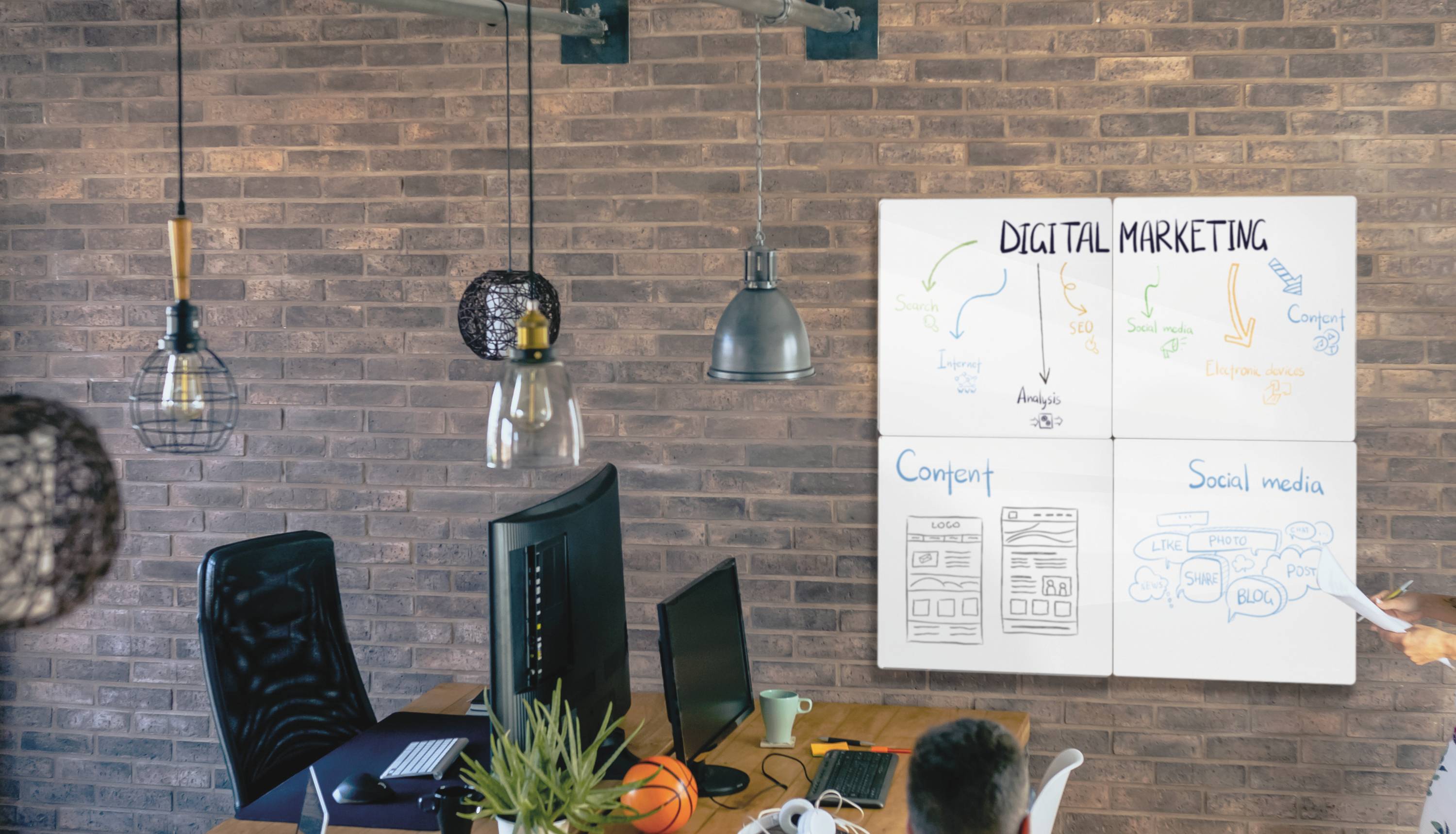 Two people in an office are looking at a whiteboard titled 'Digital Marketing', with diagrams of strategies and content sketched on it.