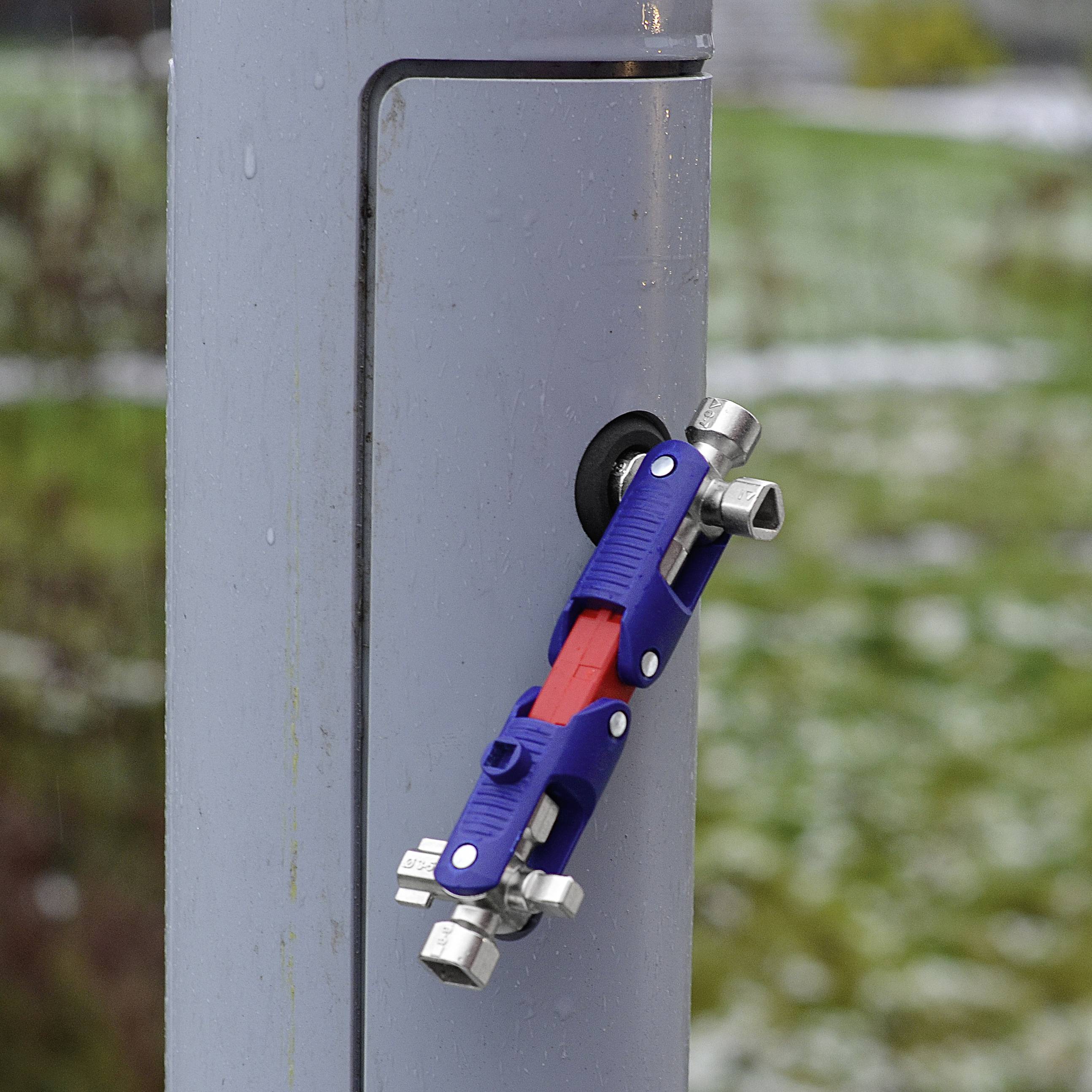 Blue padlock opened and attached to a grey metal post. Blurred background with green grass.