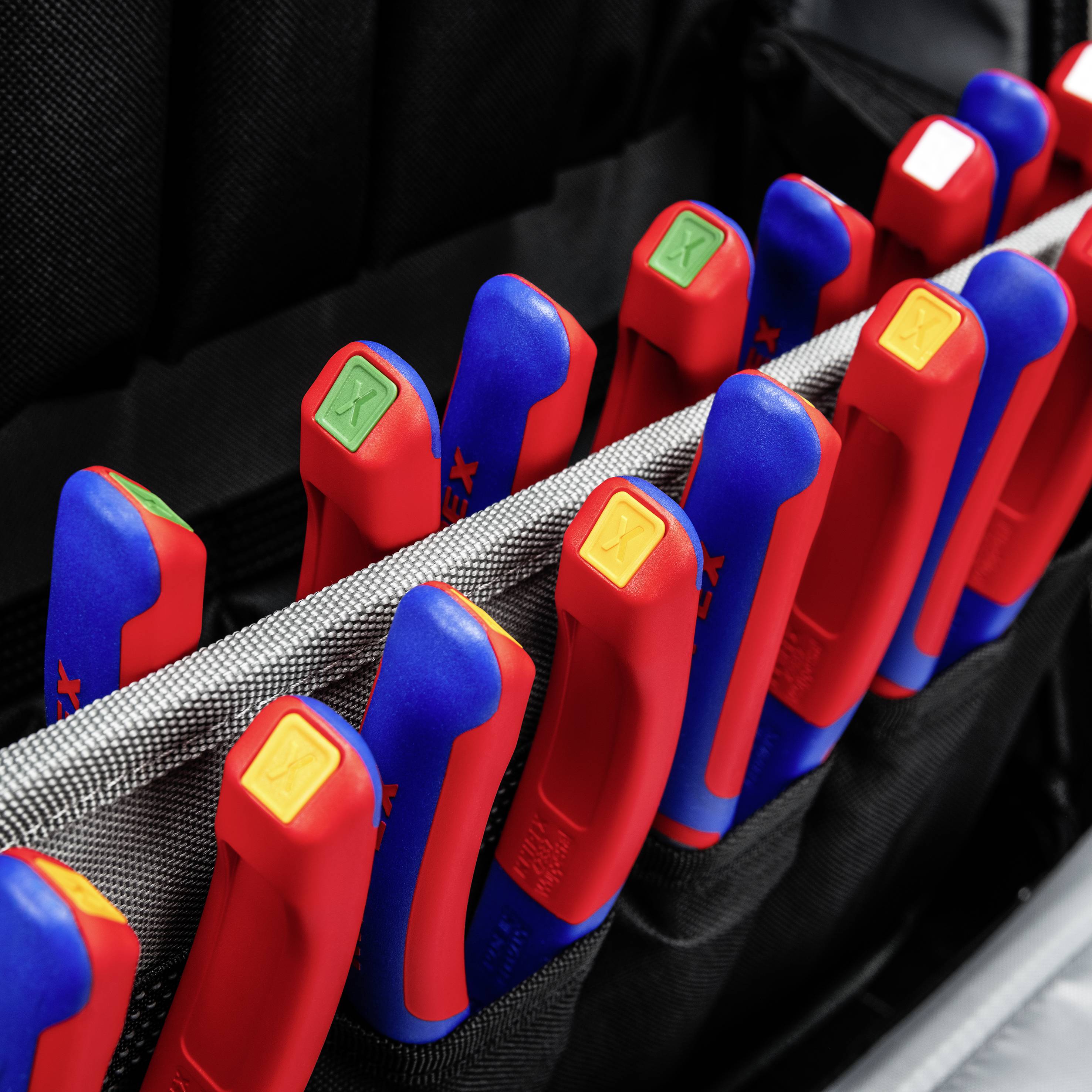 A set of colourful screwdrivers with red handles and various sizes is neatly arranged in a black bag.