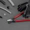 Handsaw with red handles next to black gloves on a grey background. Surrounded by cut cable pieces.