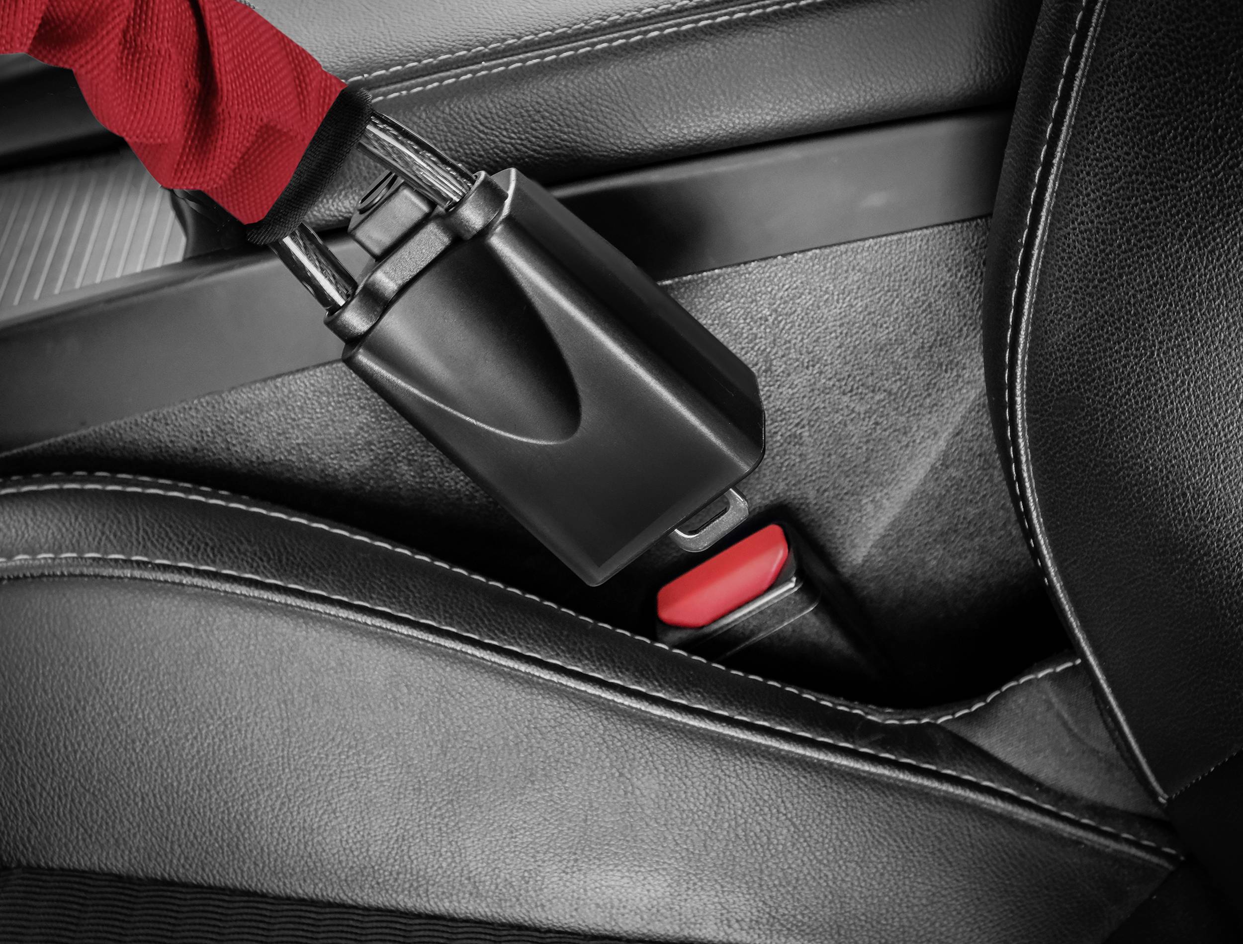 A seatbelt is inserted into a seat belt buckle. A close-up of the process in a car shows a red marking on the seat belt buckle.