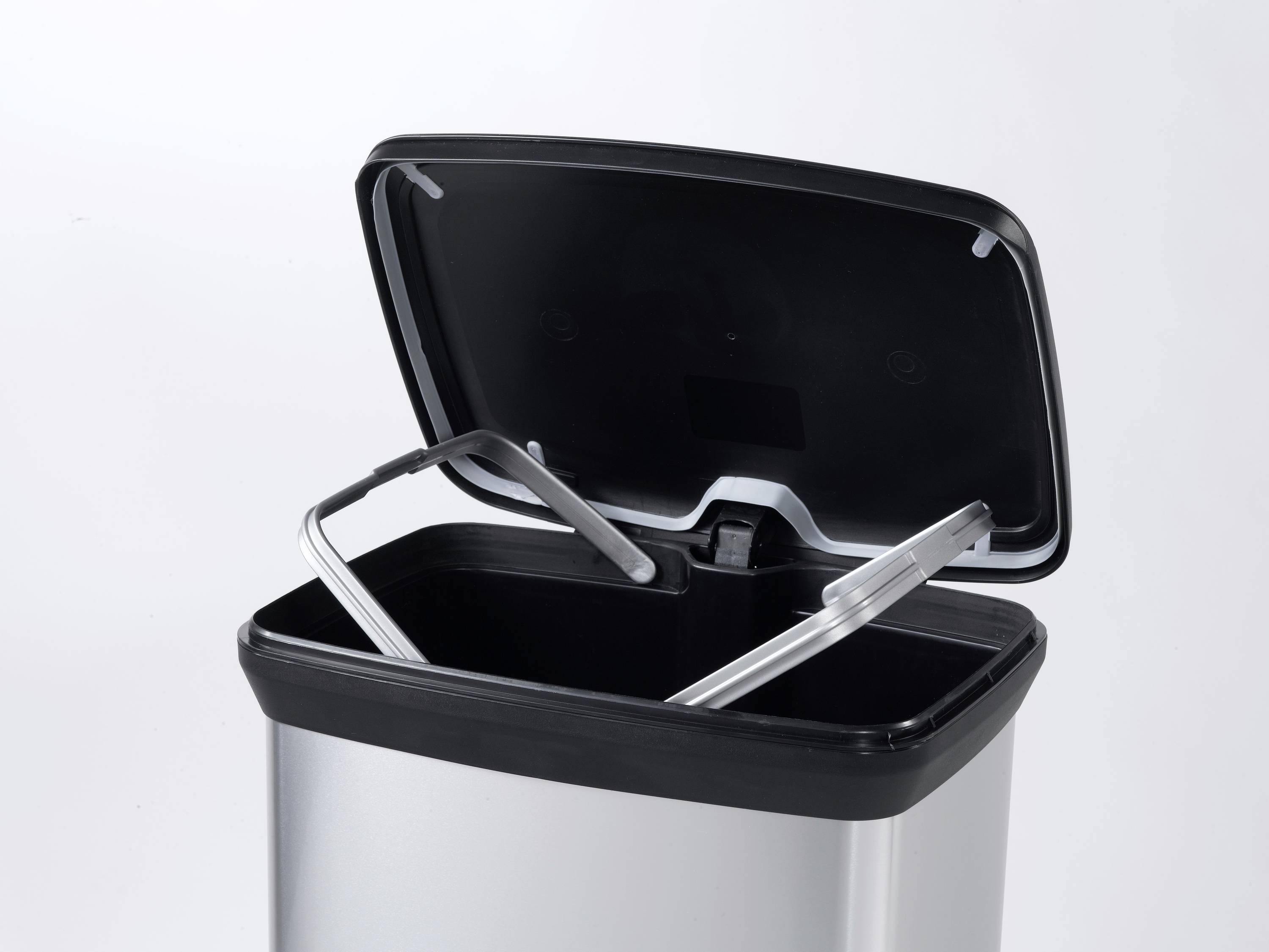 An open rubbish bin with its lid raised. The bin is empty and silver.