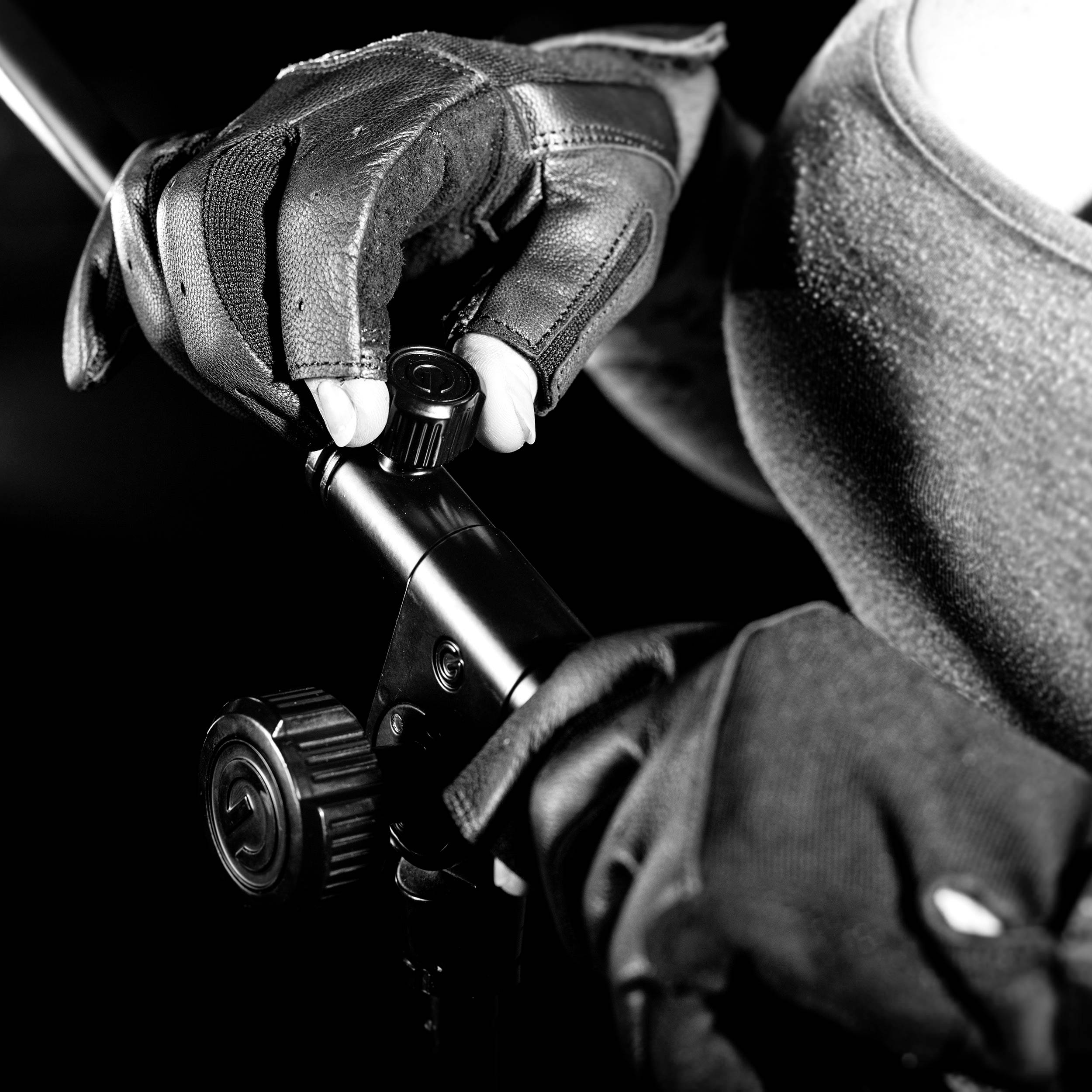 A person wearing padded gloves is holding a microphone stand. The scene is in black and white and shows the right hand in action.