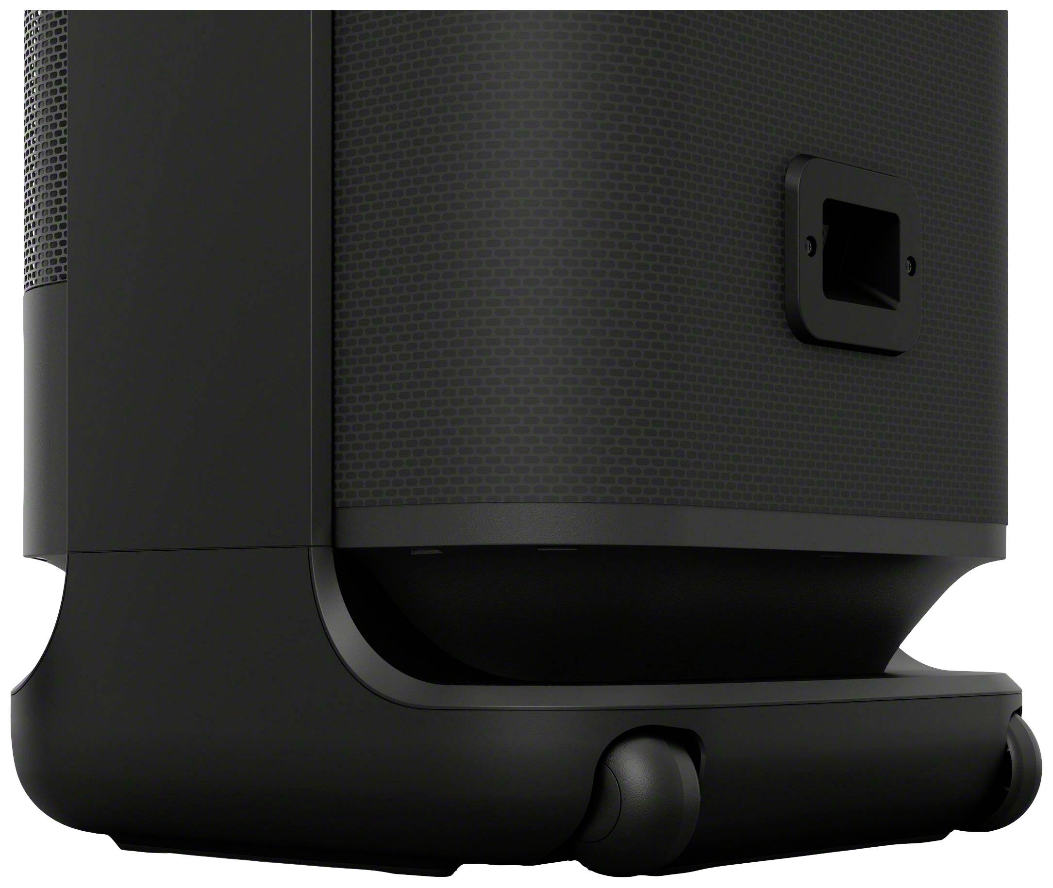 The image shows the lower part of a black speaker with a handle on the right side and a round base.