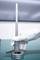 A hand wearing a white glove is holding a vertical measuring instrument positioned on a cylindrical object on a table.