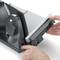 Two hands are operating an electric slicing machine, set to cut into thin slices.