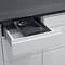 A closed white drawer beneath a dark worktop is opened, revealing a black square device with the word 'QUIR'.