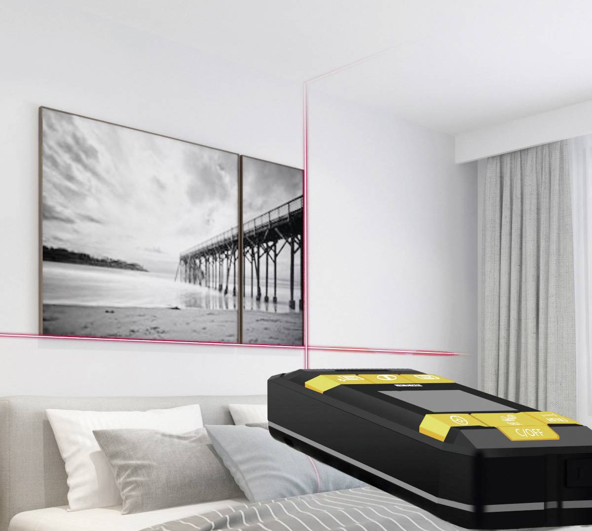 A scanner lies on a bed in a bright room. A large black-and-white landscape photograph hangs on the wall.