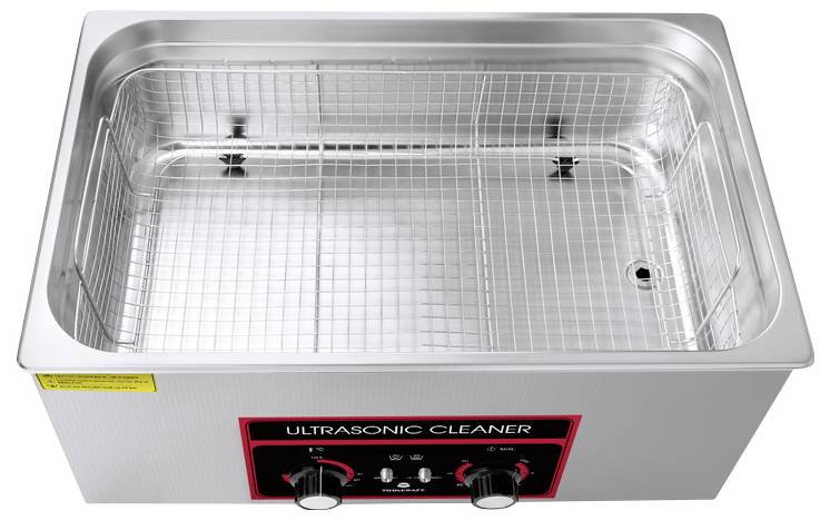 Ultrasonic cleaner with wire basket and control panel on the front, used for cleaning by means of sound waves.