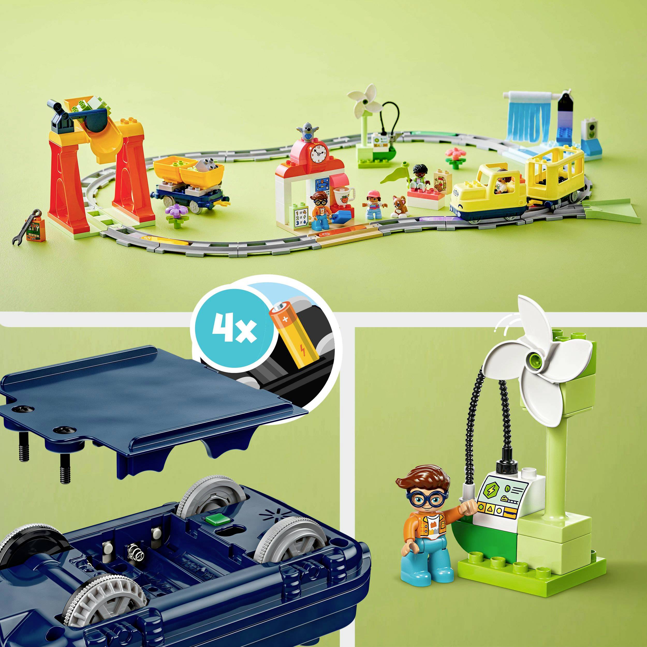 Toy train set on a green background with building blocks, tracks, figures, and a wind turbine. A child wearing glasses interacts with the set.