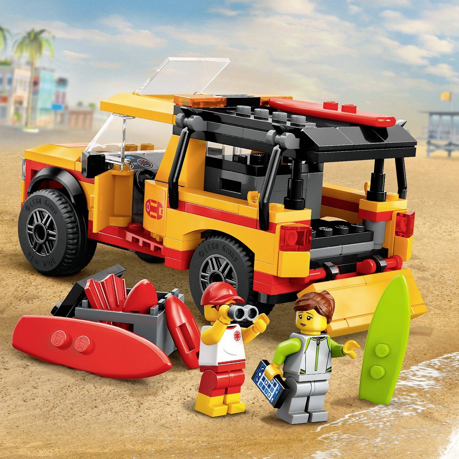 A colourful toy car sits on the beach. Next to it are two Lego figures with a surfboard and paddle. In the background, the sea and palm trees.