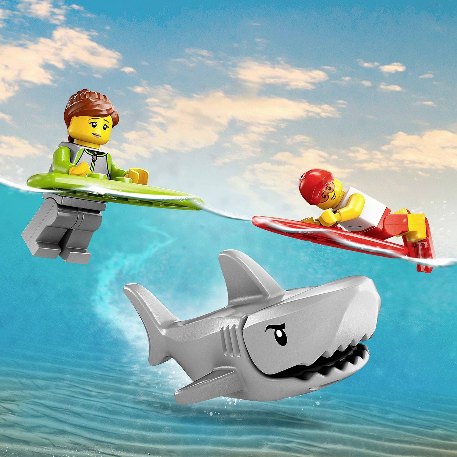 Lego figures are surfing on light blue waves, while a grey shark swims through the water beneath them.