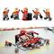 'LEGO figures in a red racing driver's suit with tyres and crew in grey overalls. Scene depicts motorsport teamwork.'
