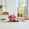 A LEGO mushroom house set sits on a table. It depicts a red and white building with surrounding vegetation and figures.