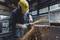 A worker is wearing protective clothing and using an angle grinder to remove metal sparks. Production hall in the background.