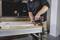 A person is fixing a hinge to a white door with an electric drill in a modern kitchen.