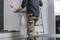 A tradesman is standing on a ladder and installing a door in the kitchen. Tools are attached to his belt.