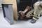 A person is assembling a piece of furniture by screwing a screw into the wood using a cordless drill driver.