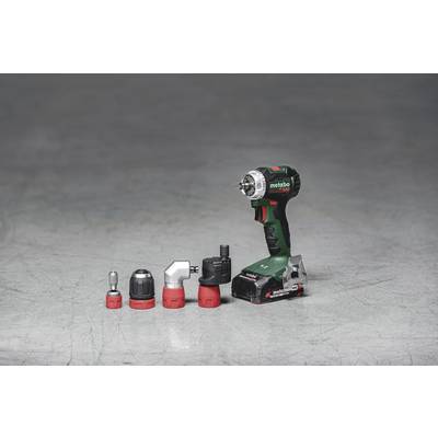 A green cordless drill with four different attachments on a grey surface.