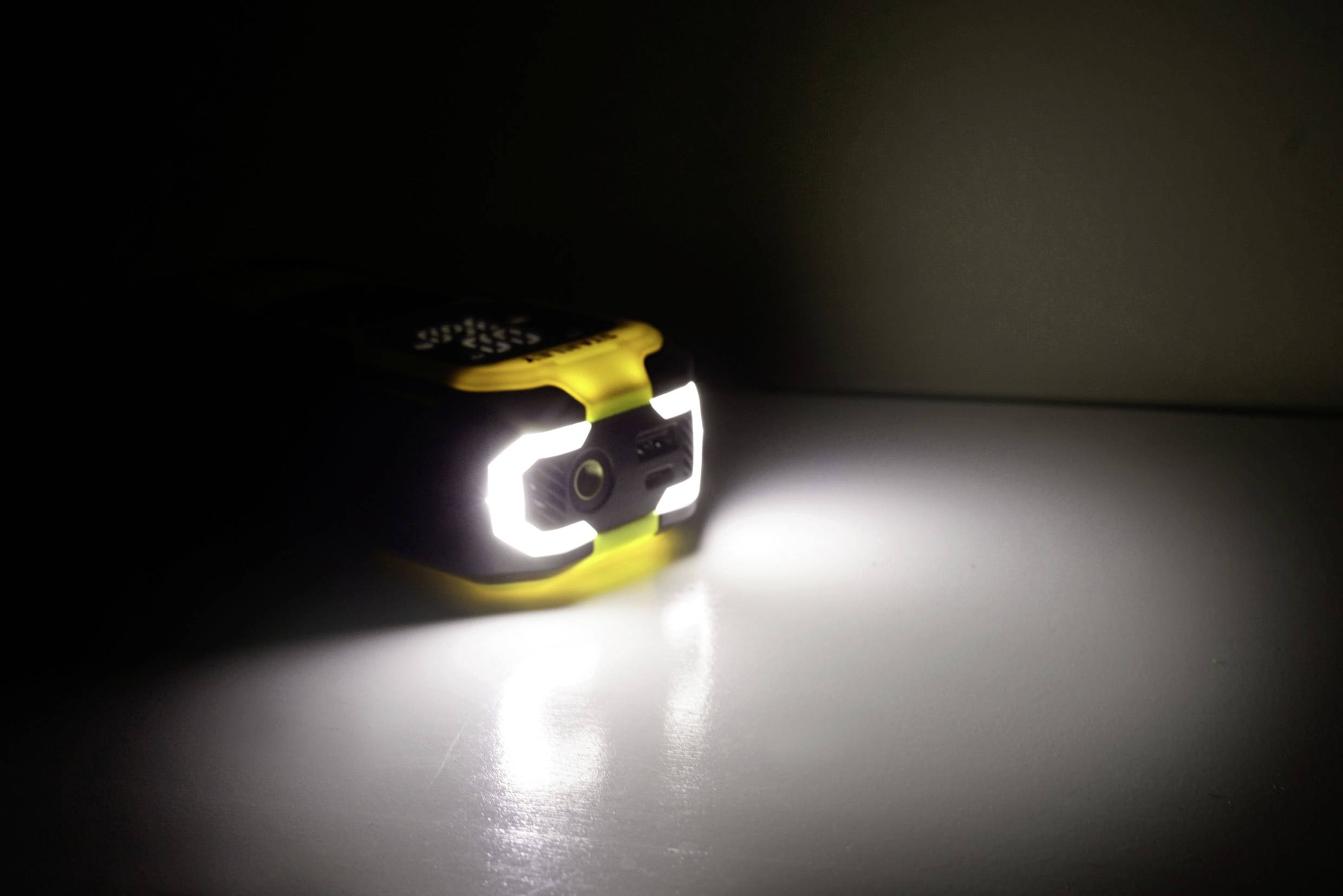 A bright LED torch on a table, casting a brilliant beam of light against a dark wall.