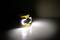 A bright LED torch on a table, casting a brilliant beam of light against a dark wall.