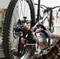 A person is lubricating the bicycle chain with a lubricant from TOOLCRAFT. The bicycle can be seen in the background.