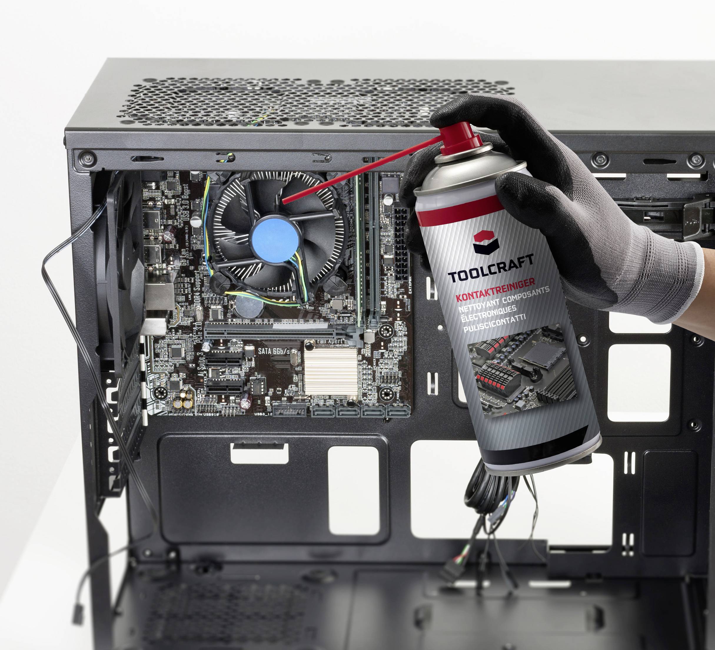 A person is using a cleaning spray to remove dust from an open computer case.