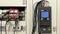 An energy logger monitors an electrical switchboard. On the left, cables and terminals are visible, on the right the digital device with measurement values.