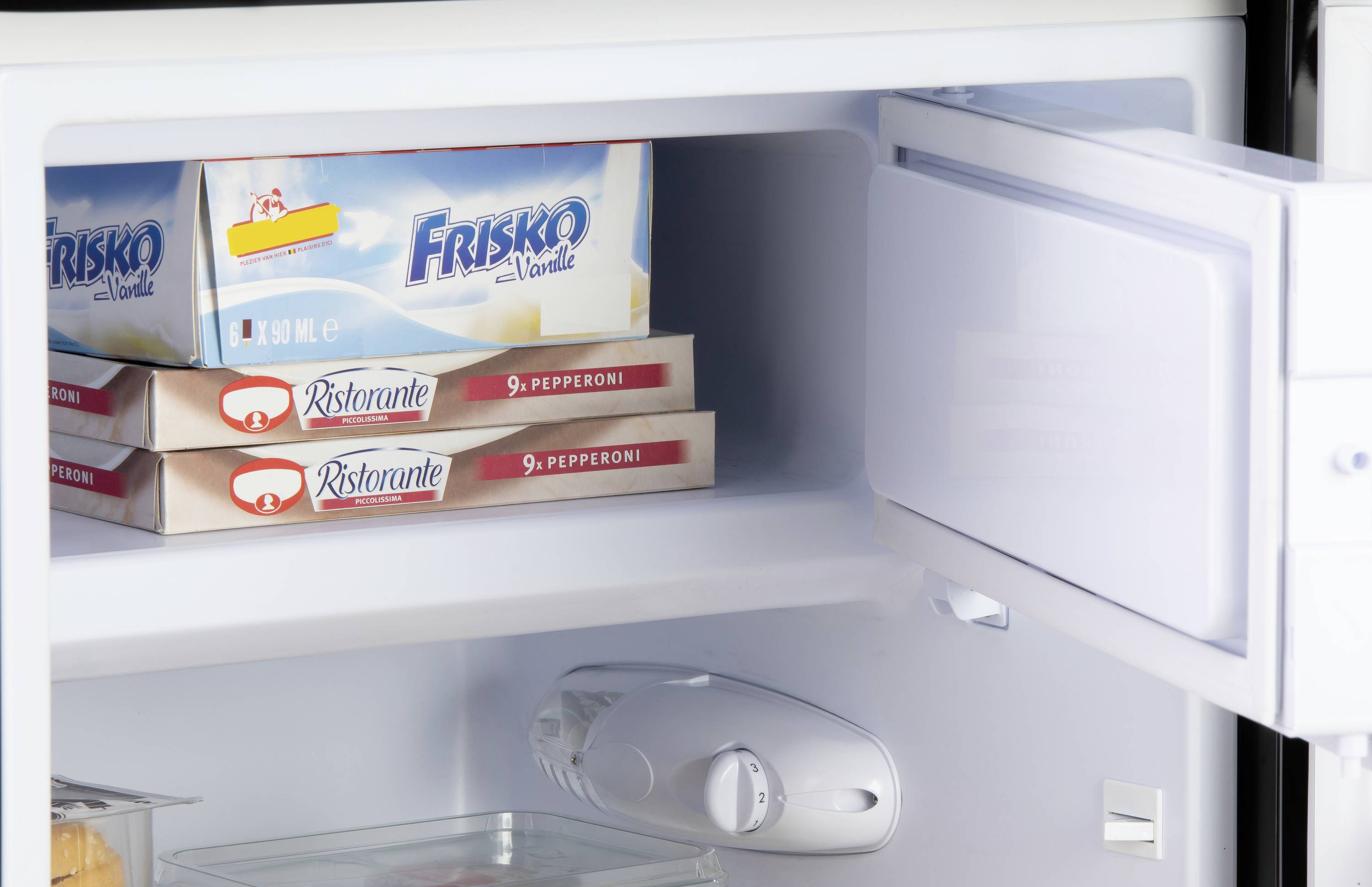 A fridge with open doors shows three pizza boxes and a tub of ice cream. An ice guard is attached to the freezer door.