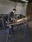 A man is grinding a metal pipe with an angle grinder in a workshop. Sparks are flying during the work. Safety glasses are being worn.