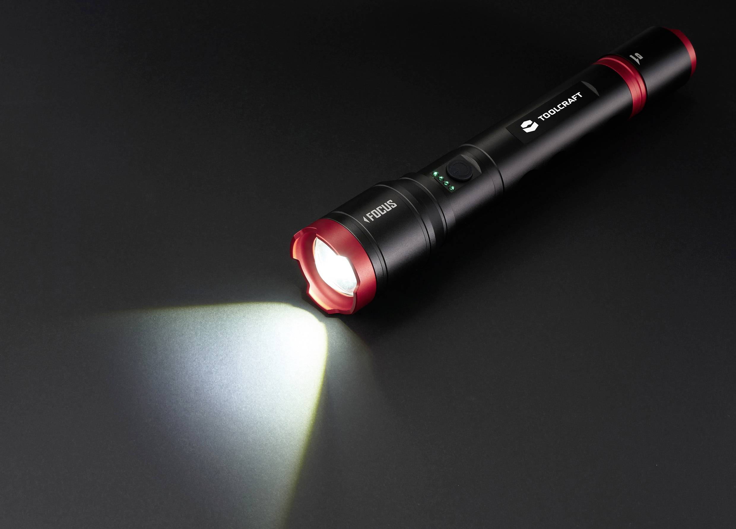 Black torch with a red border illuminates on a dark surface, casting a light beam to the left.