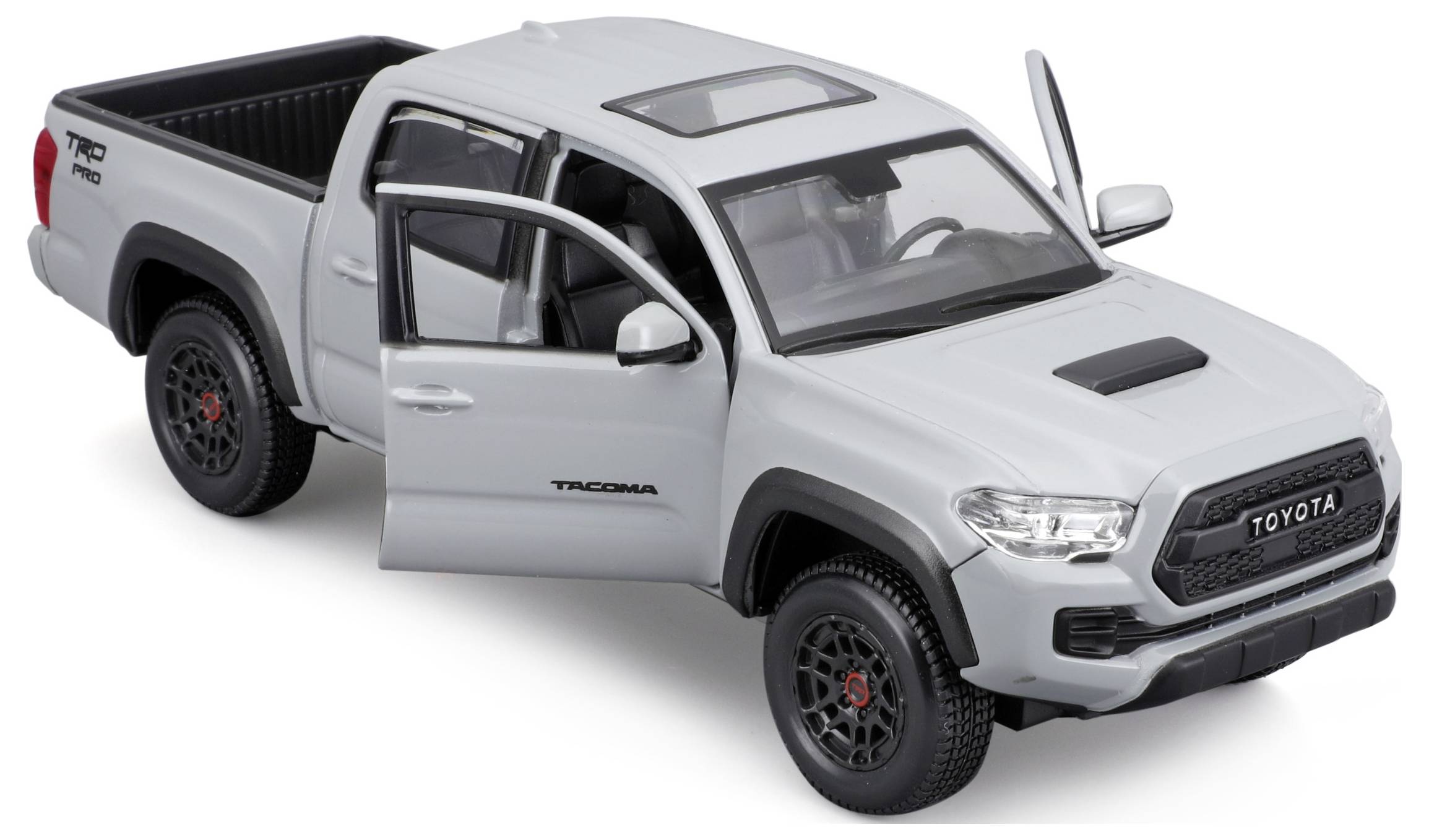 Grey toy pickup model of a Toyota Tacoma with open doors and boot, standing on a black table.