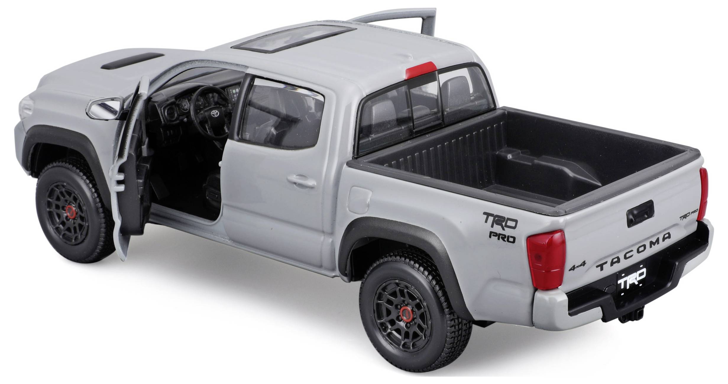 Grey model car of the pickup type with TRD Pro labelling. Passenger door open, showing interior. Loading area empty, white background.