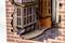 The image depicts a detailed miniature model of a building corner with brick walls, windows, and a paved walkway.