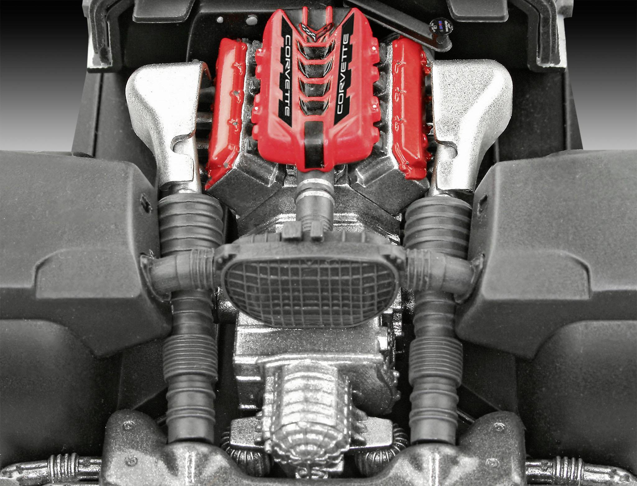 Close-up of an engine with red valve covers and a central grille, surrounded by black hoses and silver components.