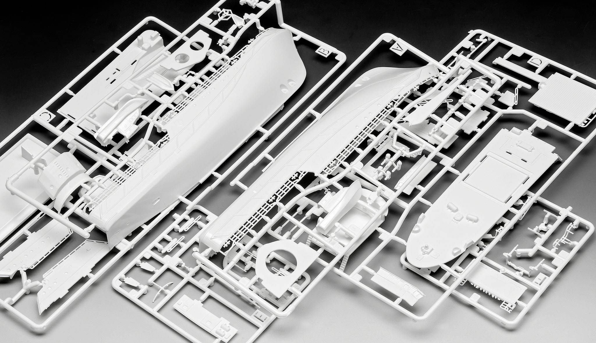 A model ship kit on a table, consisting of several white plastic parts that still need to be assembled.