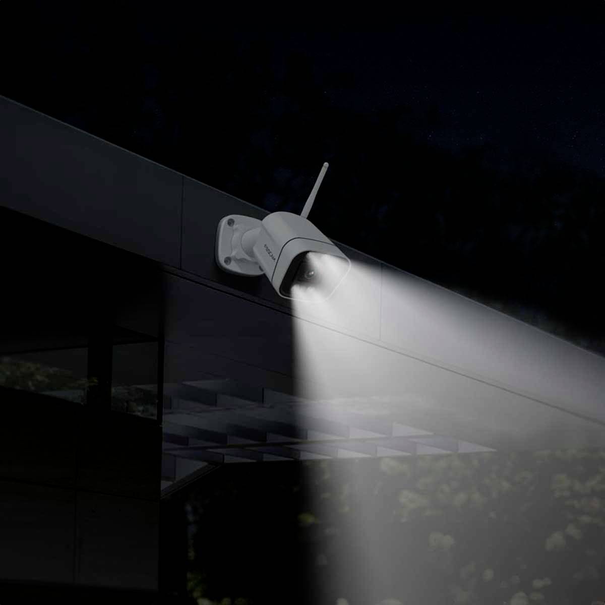 Security camera mounted on a building, illuminating the area below in the darkness.