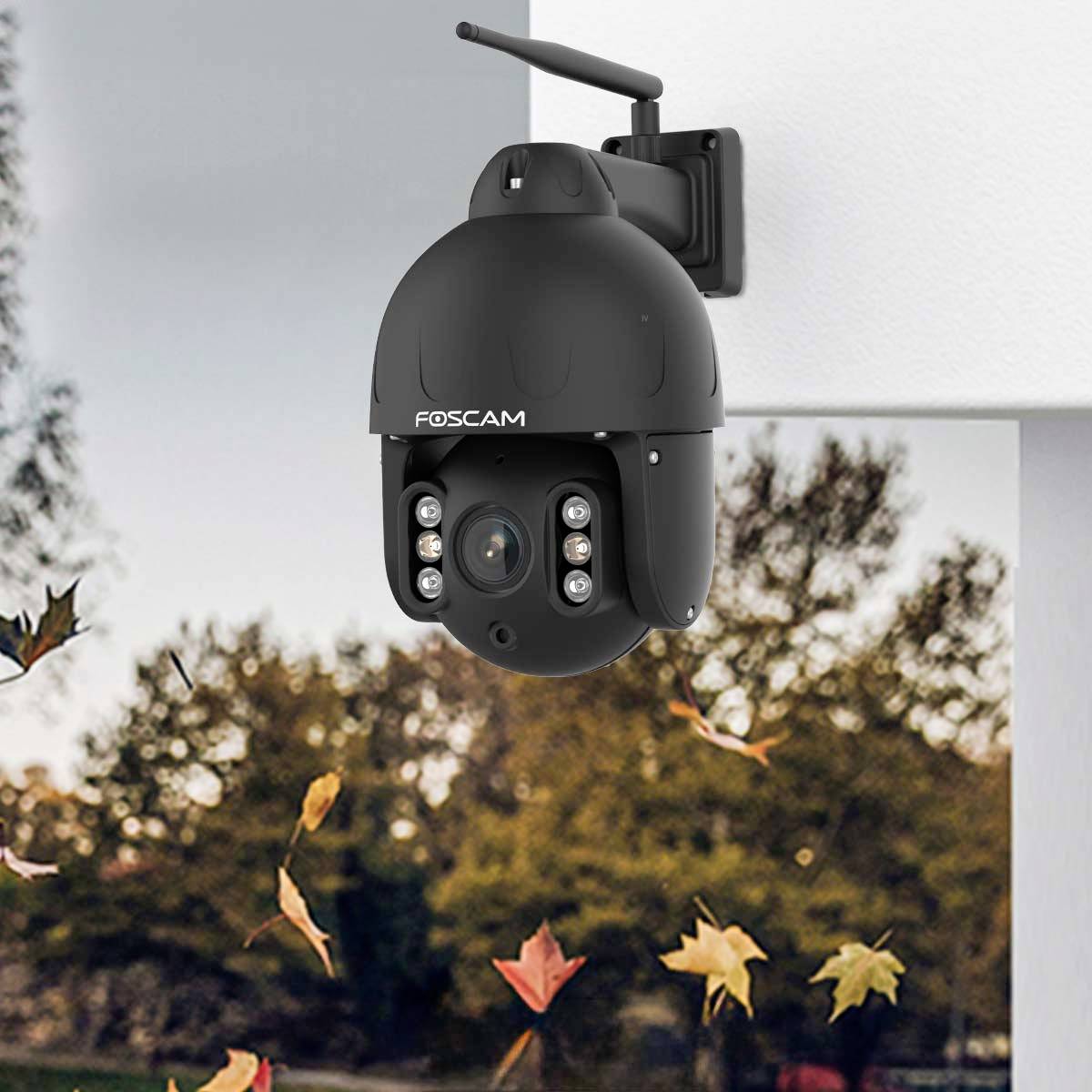 Security camera mounted on a wall, surrounded by autumnal foliage in the background.