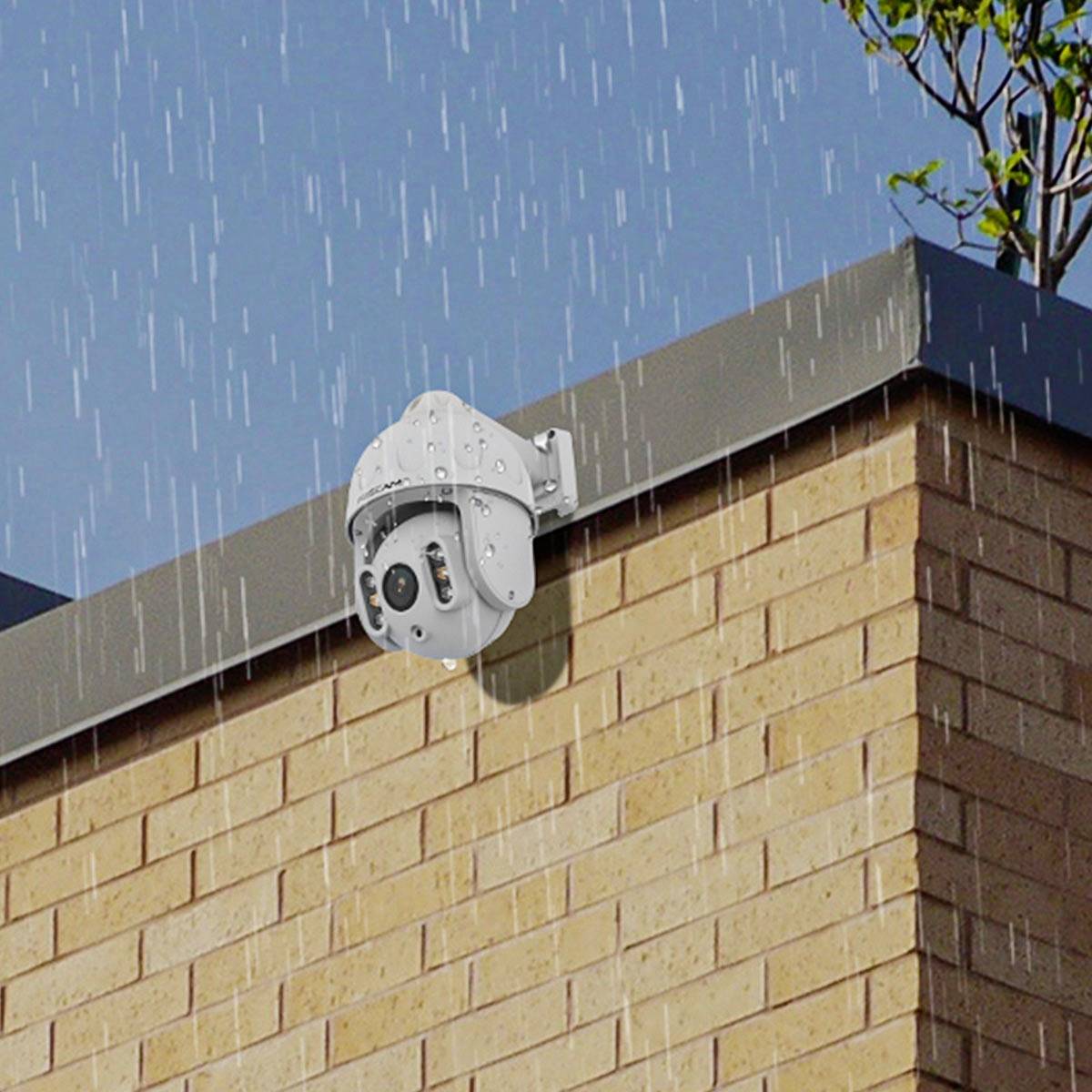A security camera is mounted on the exterior of a brick building while it is raining.