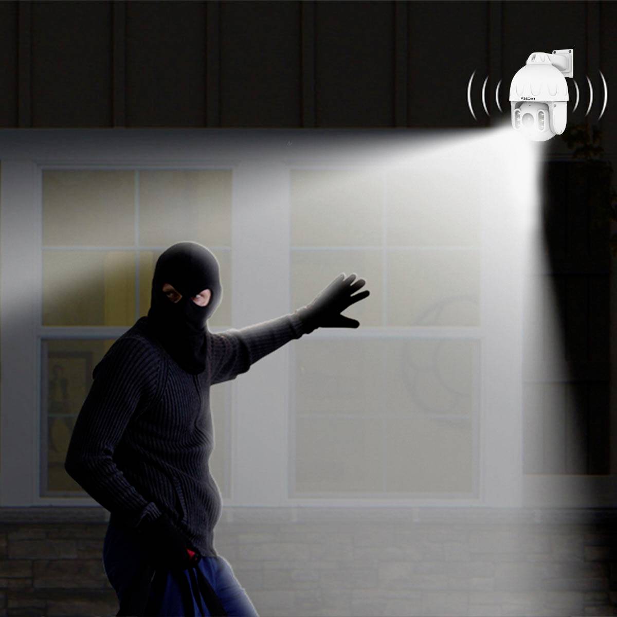 A person wearing dark clothing and a mask is detected by a security light with an integrated motion sensor in a garden.