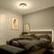 Bedroom with a double bed, dark bedspread, wooden furniture and wall decorations. Soft lighting creates a cosy atmosphere.