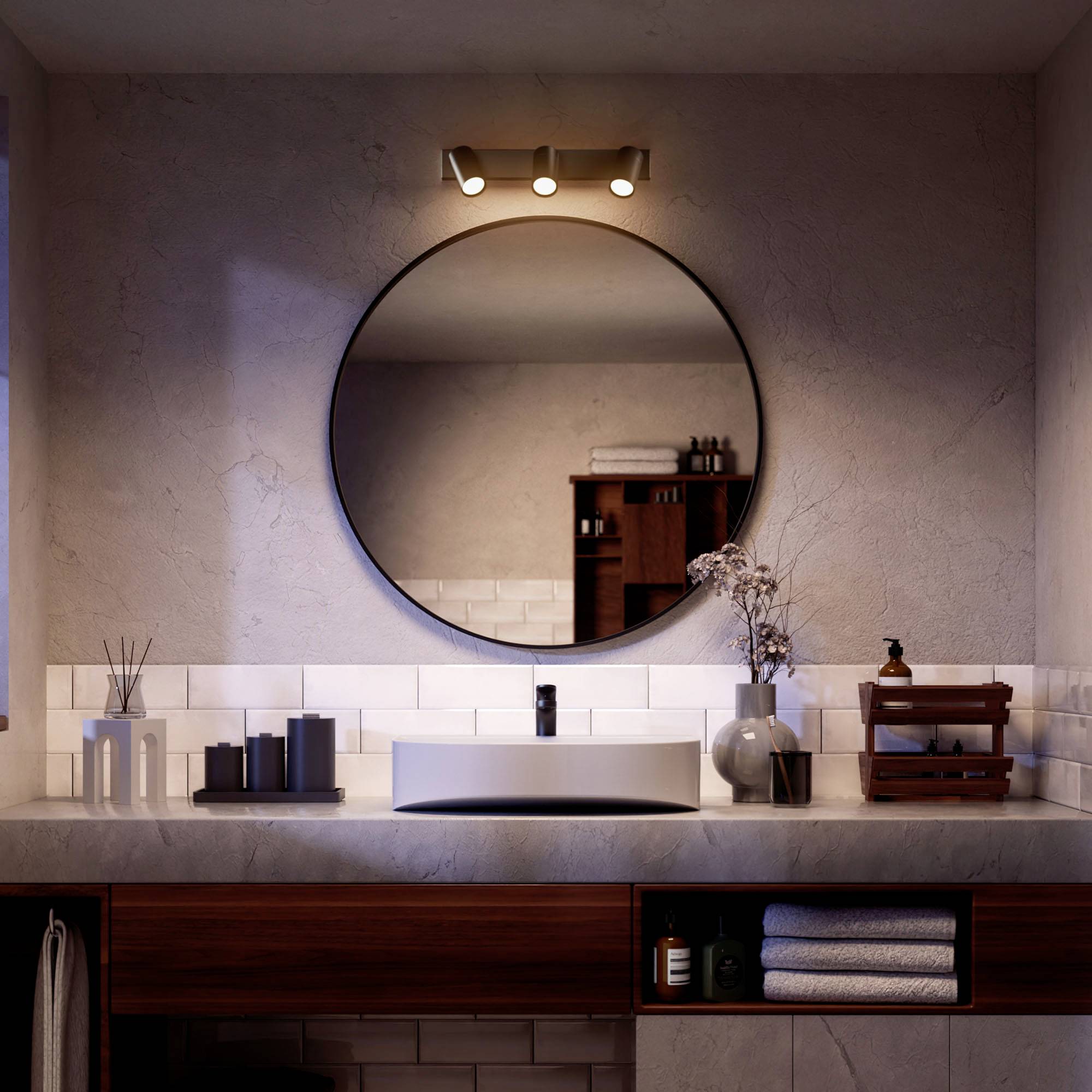 A stylish bathroom with a round mirror, basin, and modern lighting. Vases and towels are placed on the countertop.