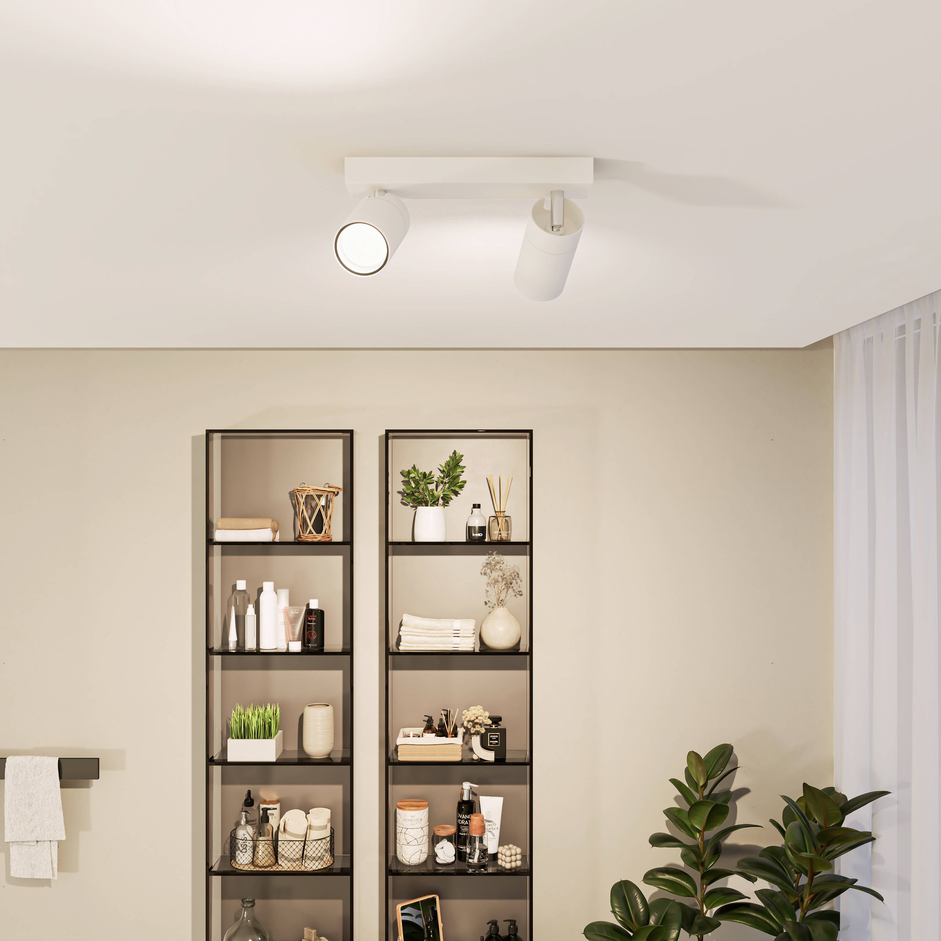 A modern-designed bathroom shows a shelf with toiletries, plants, and towels, with a towel rail beside it.