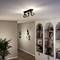 An elegant living room lighting setup with three spotlights on the ceiling. Beside it stands a bookshelf and plants, creating a cosy atmosphere.