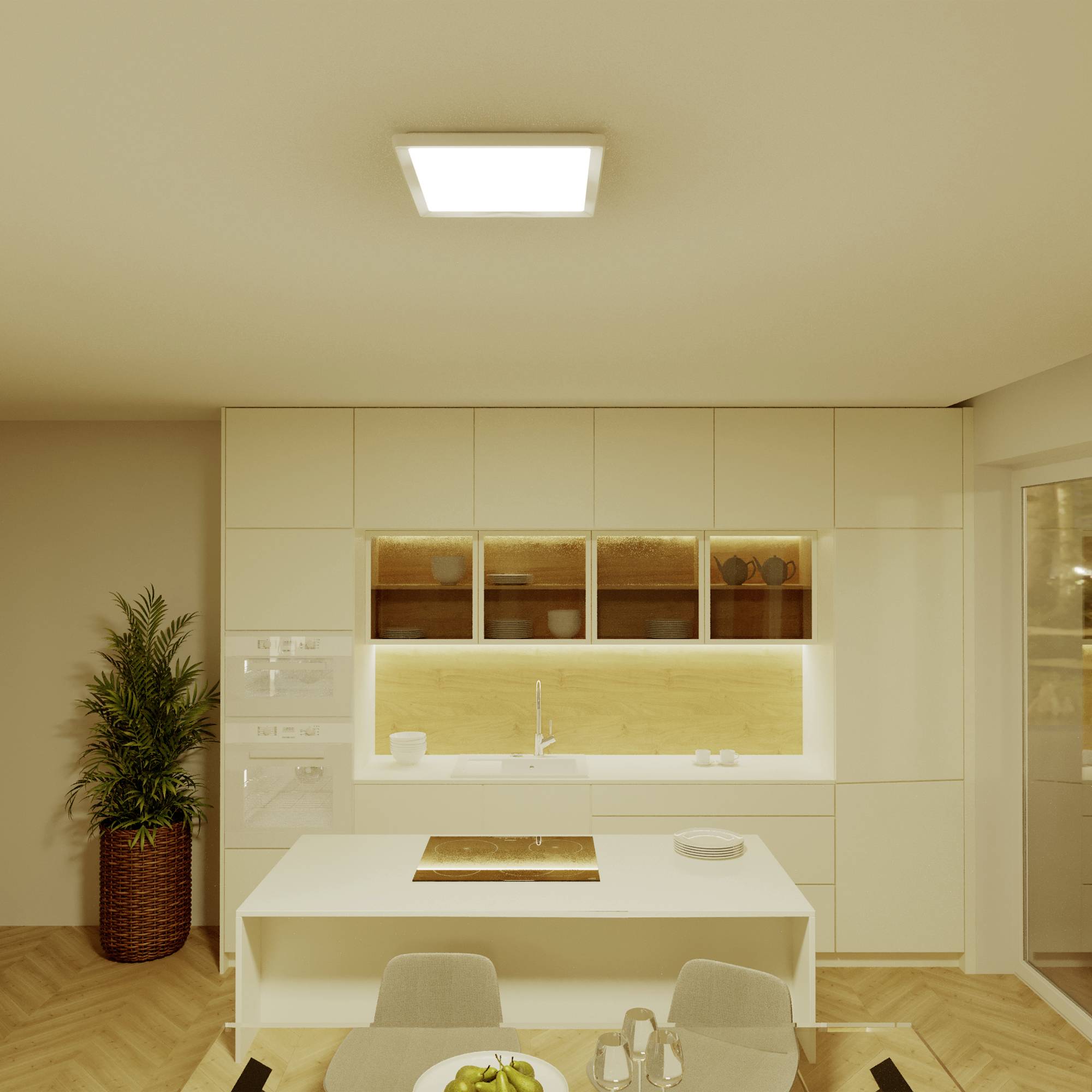 Kitchen with white cupboards, illuminated worktop, small table with chairs and a plant in the corner.