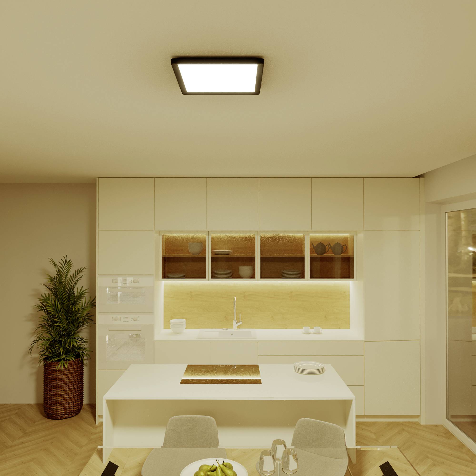 Modern kitchen with an illuminated kitchen island, white cupboards and a dining table in the foreground. A plant stands to the left.
