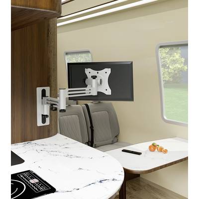 Adjustable TV mount fixed to a motorhome wall, displaying a screen, with a seating area and table nearby, and a green landscape visible outside.