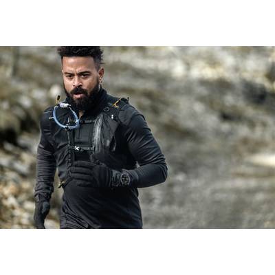 A man is jogging along a rocky path, wearing black sportswear and a watch.