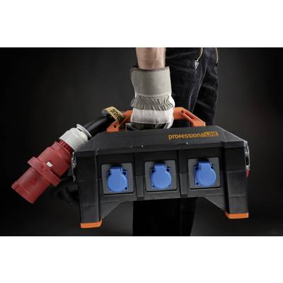 A person is holding a black and orange multi-socket extension with blue sockets and a red industrial plug.